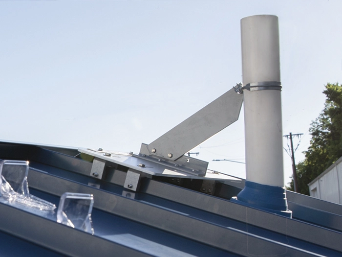 VentSaver metal roof vent protection installed beside a vent pipe on a blue metal roof